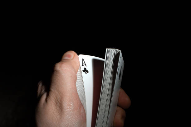 istock hand flips a deck of poker cards on a black background copy space. close up 1205302888