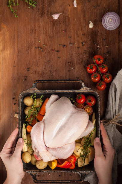 istock Uncooked whole chicken with vegetables ready for baking. Table setting with Christmas decorations. Rustic style. 1205303261