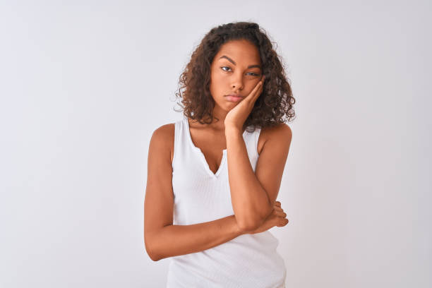 young brazilian woman wearing casual t-shirt standing over isolated white background thinking looking tired and bored with depression problems with crossed arms. - dull colors imagens e fotografias de stock