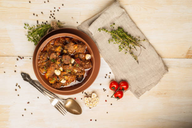 istock Braised meat with vegetables in a thick sauce. A large portion in a deep plate is ready to eat. Rustic decoration on a dark wooden background. 1205304256