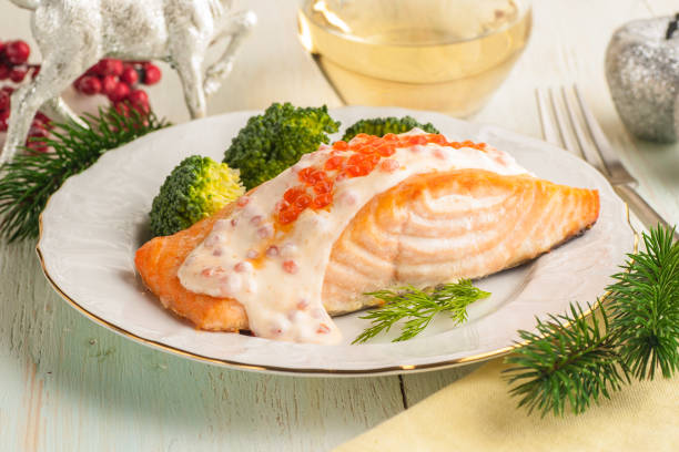 istock Baked salmon fillet with broccoli and creamy sauce. Main course for lunch or dinner with Christmas decorations. 1205304749