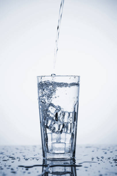 istock Clear mineral water splashes in a glass with ice. Fluid in motion. 1205306422