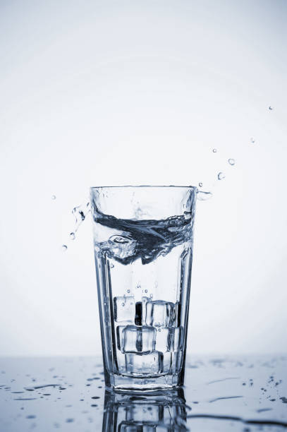 istock Clear mineral water splashes in a glass with ice. Fluid in motion. 1205306509