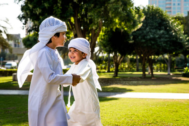 Group of middle eastern kids in Dubai Group of middle-eastern kids wearing white kandora playing in a park in Dubai - Happy group of friends having fun outdoors in the UAE arab culture stock pictures, royalty-free photos & images