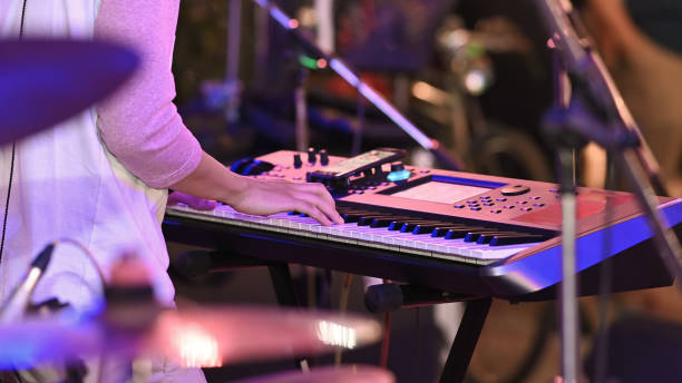 istock Closeup night musician working as electrical pianist while sitting and playing at his electric piano with the blurred night stage as background. 1205311215