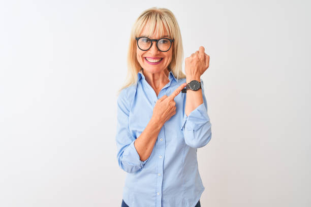 imprenditrice di mezza età che indossa camicia elegante e occhiali su sfondo bianco isolato in fretta indicando il tempo di guardare il tempo, impazienza, guardando la fotocamera con espressione rilassata - checking the time women impatient wristwatch foto e immagini stock