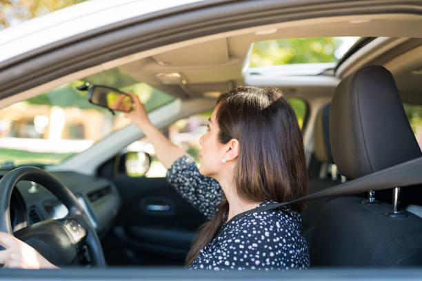 istock Woman Adjusting Mirror In Car 1205313668