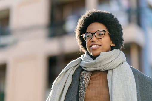 A portrait of a young confident black woman with afro hair while looking away in winter warm clothing.