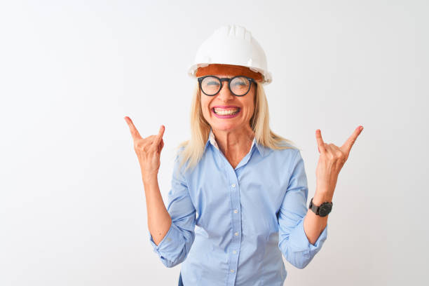 istock Middle age architect woman wearing glasses and helmet over isolated white background shouting with crazy expression doing rock symbol with hands up. Music star. Heavy concept. 1205314509