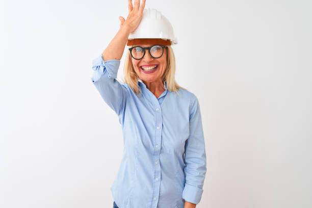 istock Middle age architect woman wearing glasses and helmet over isolated white background surprised with hand on head for mistake, remember error. Forgot, bad memory concept. 1205314608