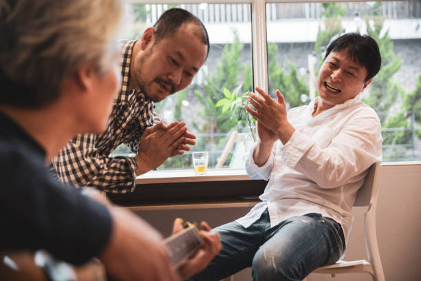 Mature korean men having fun playing guitar and singing at home