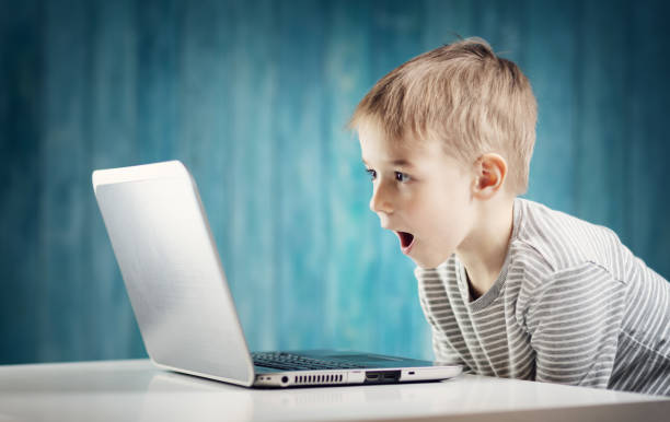 istock happy five years old child sitting with a laptop at table 1205315858