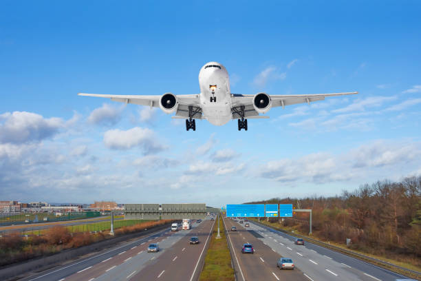 istock Large passenger aircraft landing over high speed highway. 1205315908