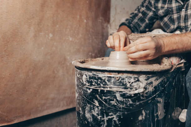 istock Man forms a white clay product on a pottery wheel 1205317222