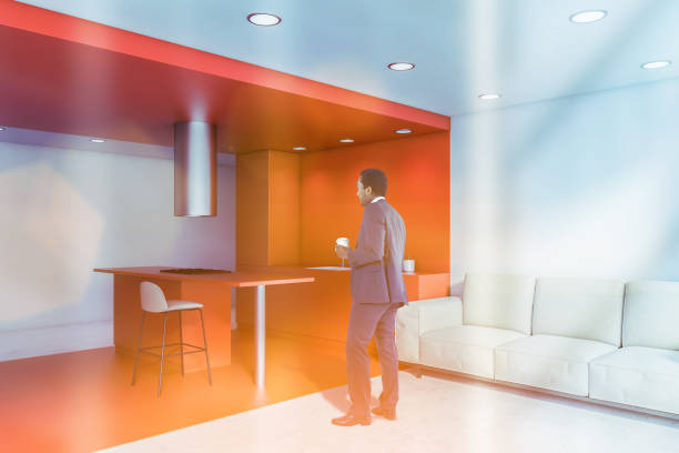 istock Man in orange kitchen with bar and sofa 1205317700