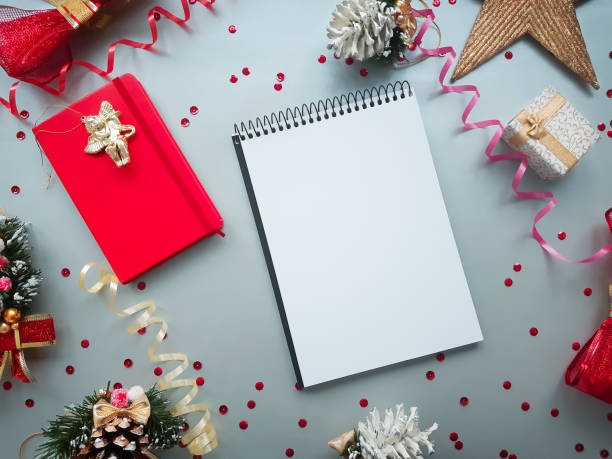 istock Christmas and New Year decorative composition. Top view, background with copy space for your text. Christmas bows, notebook, gift, angel, star, pine cone, tapes on a grey background with paillettes. 1205317825