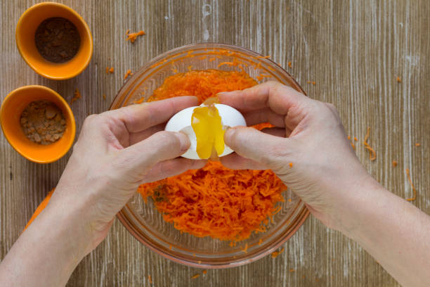 istock Woman hands put raw egg from broken egg into grated carrot batter for carrot pie on the wooden background 1205318420