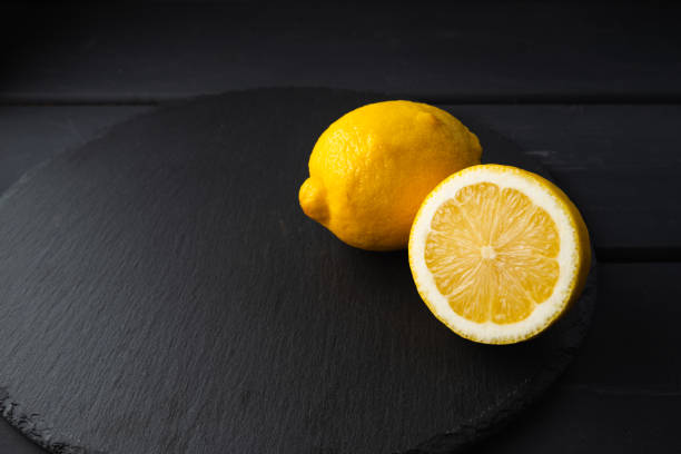 istock Fresh lemon cut in half on a black background 1205324996