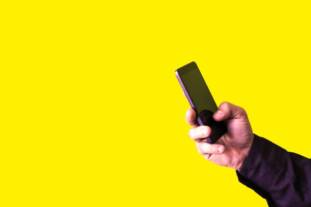 istock Man is holding smartphone in hands isolated on yellow background. Addicted to technologies. 1205326636