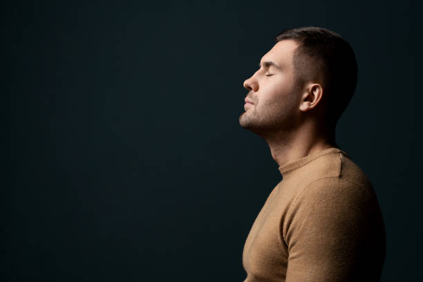 istock Male model dramatic and tries to relax, keeps eyes closed isolated over background . Calm peaceful concept 1205327312