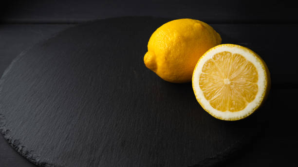 istock Fresh lemon cut in half on a black background 1205327525