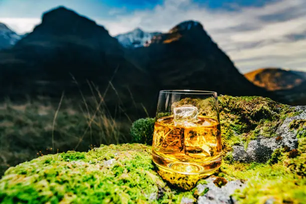 Glass of whisky with ice at Glencoe, Scotland on a cold February day. The view is east towards the Meeting of the Three Waters.