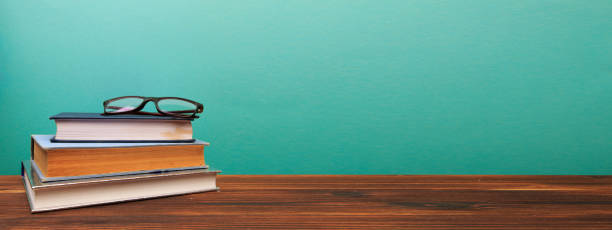 istock pile of old books with glasses panorma, good copy space  on blue background - Image 1205337119