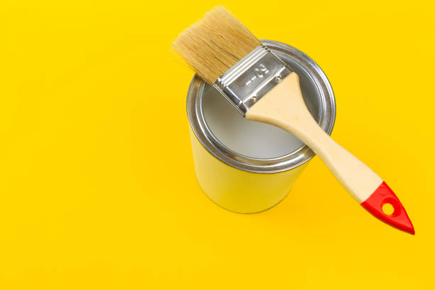 istock White Paint Can with Brush Top View On Yellow Background. 1205337169