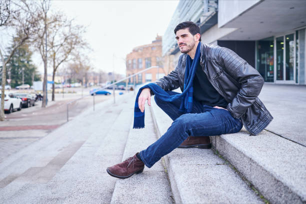 istock well-dressed young man sitting on a staircase looking at the horizon thoughtfully 1205337170