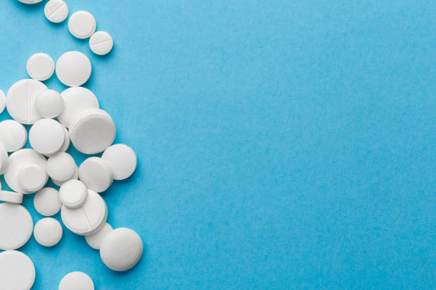 istock scattered white pills on a blue table. Layout for special offers such as advertising or other ideas. The concept of medicine, pharmacy and healthcare. Space for copy. 1205338613