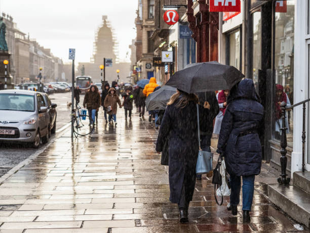 Rainy weather on George Street in Edinburgh Edinburgh, Scotland - Pedestrians caught in heavy rain on George Street, one of Edinburgh's most popular shopping streets. st george street stock pictures, royalty-free photos & images
