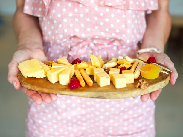 Woman holding cheese plate in her hands. Close up. Summer party