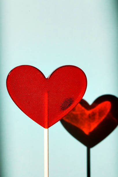 istock red heart as lollipop candy on blue background. Valentines day minimalist background 1205342330