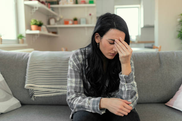 Having Panic Attack Frustrated young woman suffering from the headache while sitting on the sofa at home with an expression of being unwell, with eyes closed. nausea photos stock pictures, royalty-free photos & images