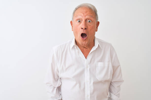 istock Senior grey-haired man wearing elegant shirt standing over isolated white background afraid and shocked with surprise expression, fear and excited face. 1205342886