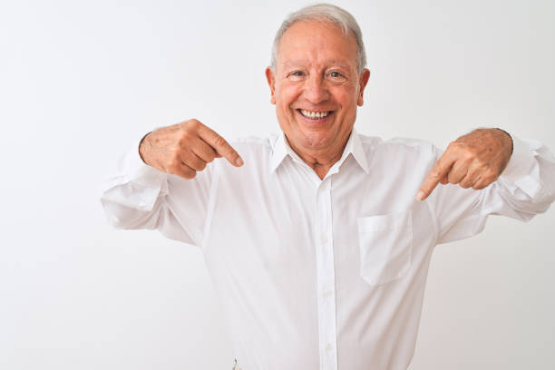 istock Senior grey-haired man wearing elegant shirt standing over isolated white background looking confident with smile on face, pointing oneself with fingers proud and happy. 1205343022