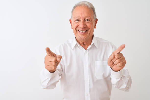 istock Senior grey-haired man wearing elegant shirt standing over isolated white background pointing fingers to camera with happy and funny face. Good energy and vibes. 1205343025