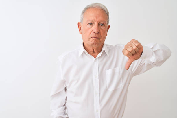istock Senior grey-haired man wearing elegant shirt standing over isolated white background looking unhappy and angry showing rejection and negative with thumbs down gesture. Bad expression. 1205343079