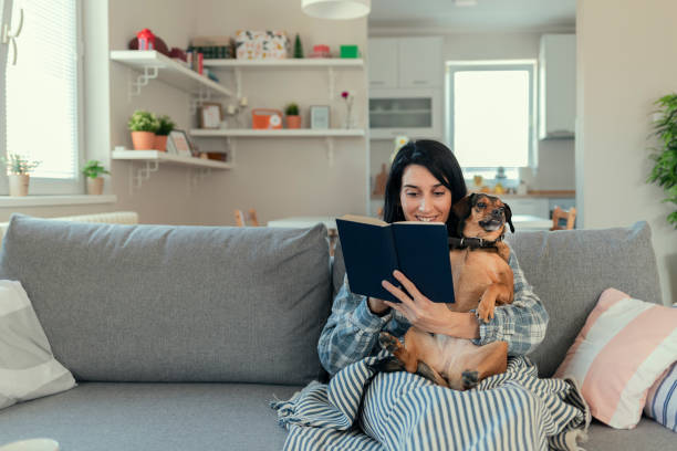 istock Woman Reading at Home With Her Cute Dog 1205343295