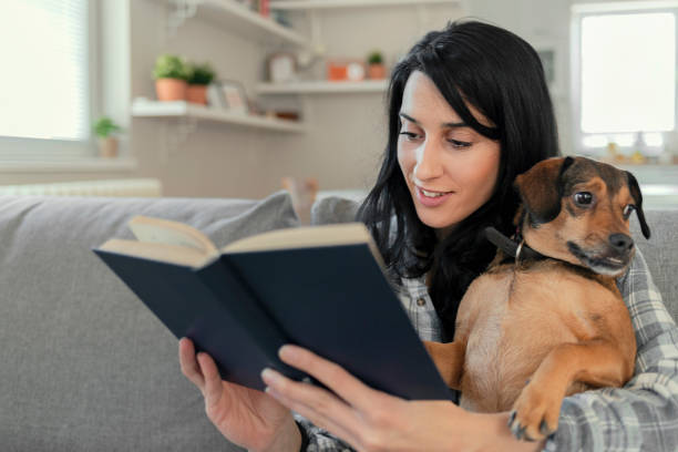 istock Woman Reading at Home With Her Cute Dog 1205344313