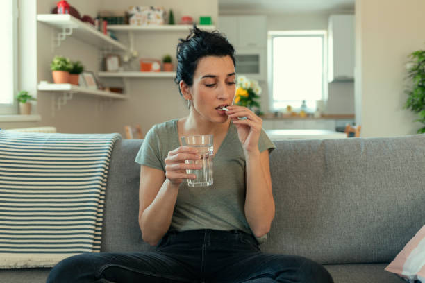 Young Woman Taking a Pill Woman taking tablet with glass of fresh water. Close up of woman holding a glass of water and medication in her hand birth control pill stock pictures, royalty-free photos & images