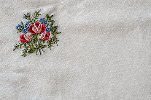 white cotton fabric with hand-embroidered roses and forget me not