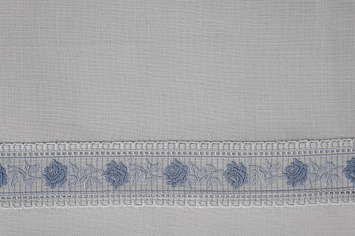 Embroidered border with roses in blue white on a white cotton table cloth