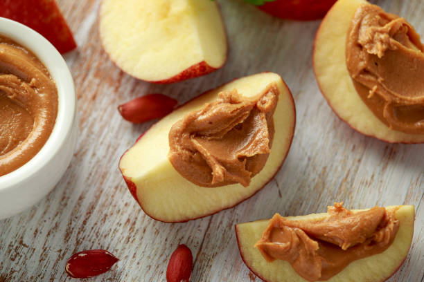 istock Peanut butter and apple to snack. on white wooden board 1205349454