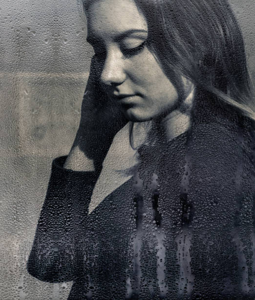 istock Young woman viewed through moisture on a window 1205349592