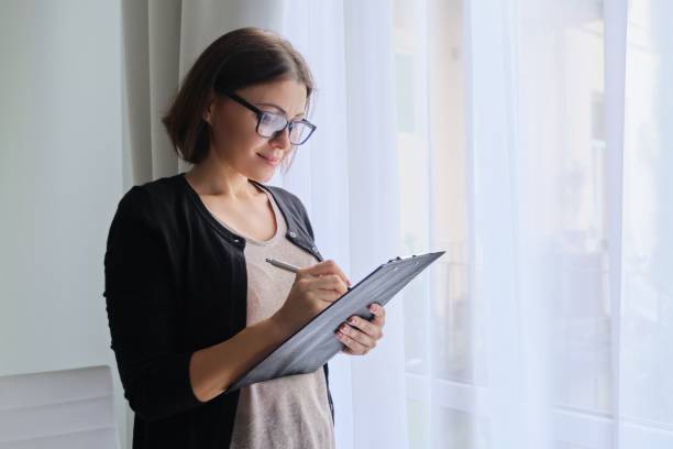 istock Mature woman couch taking notes standing near window in office 1205351138