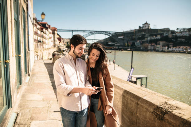 istock Young couple walking while looking at a smartphone 1205351178