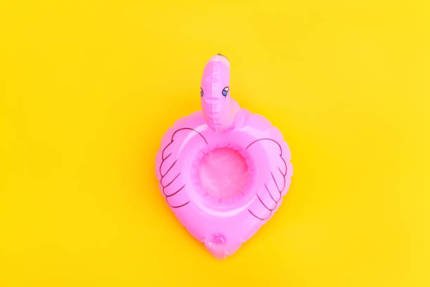 istock Summer beach composition. Simply minimal design with pink Inflatable flamingo isolated on yellow background. Pool float party, trendy celebrity fashion concept. Flat lay top view copy space 1205353377