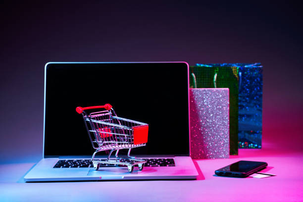 istock Laptop with custumers trolley, gift packet, phone and pay card on the table in modern neon colors. 1205354316