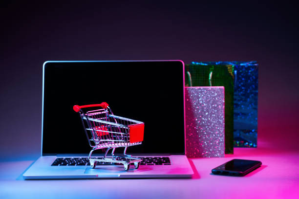 istock Laptop with custumers trolley, gift packet and phone on the table in modern neon colors. 1205354749